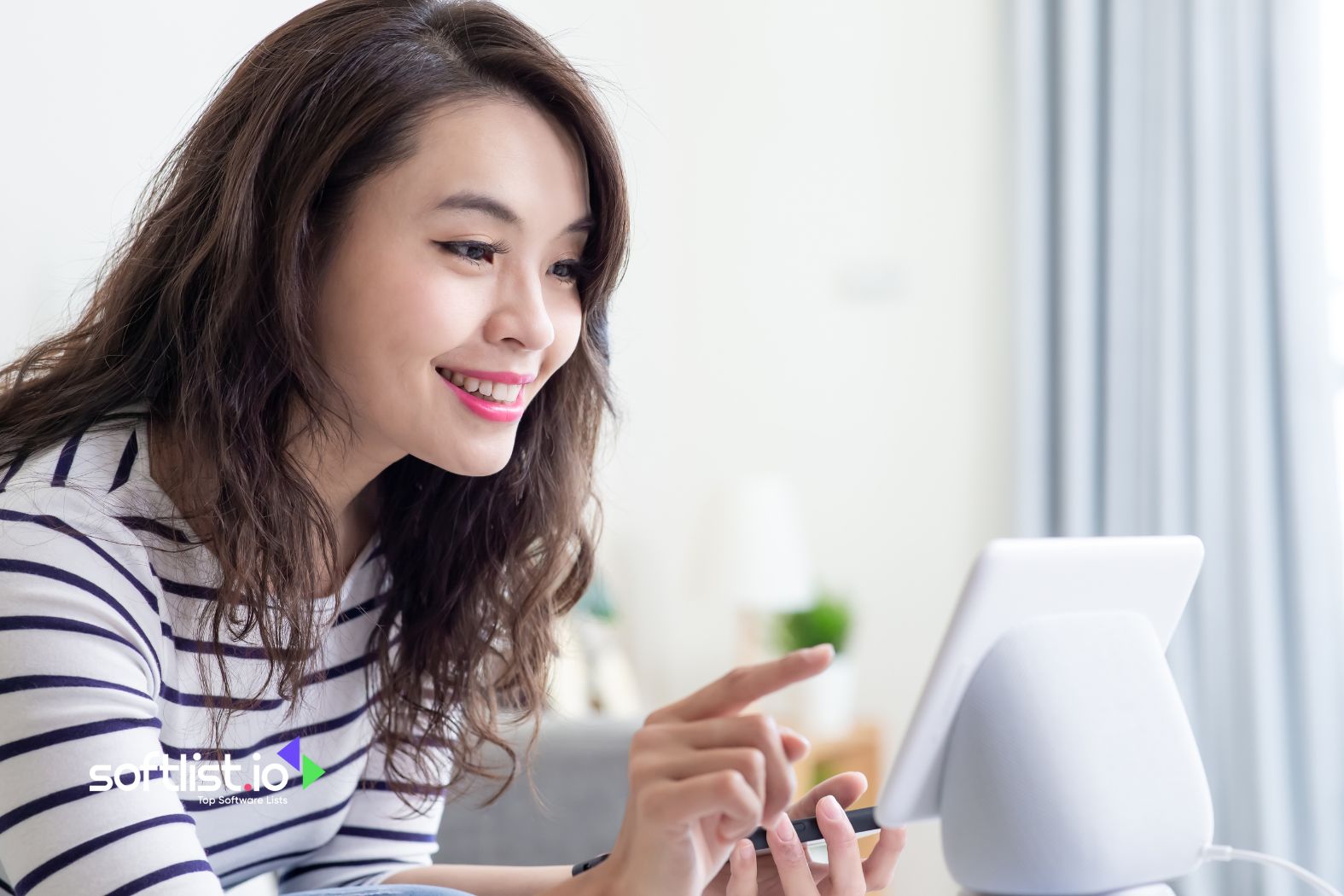 A smiling woman interacting with a tablet in a bright, cozy room