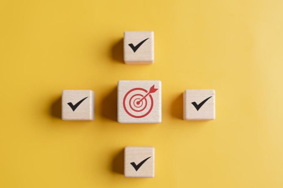 Wooden blocks with check marks and a target on a yellow background.