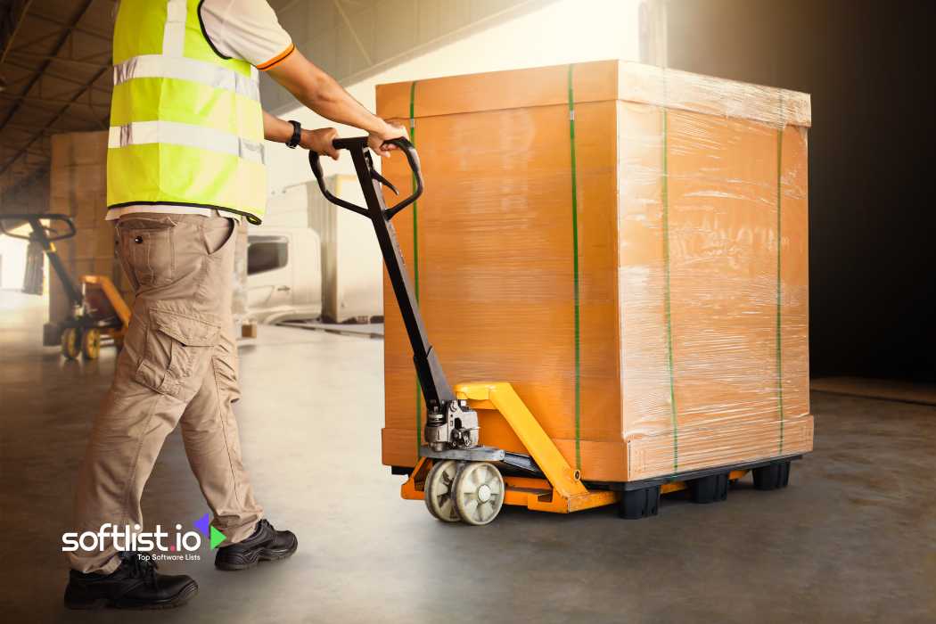 Worker moving a large box on a pallet jack in a warehouse