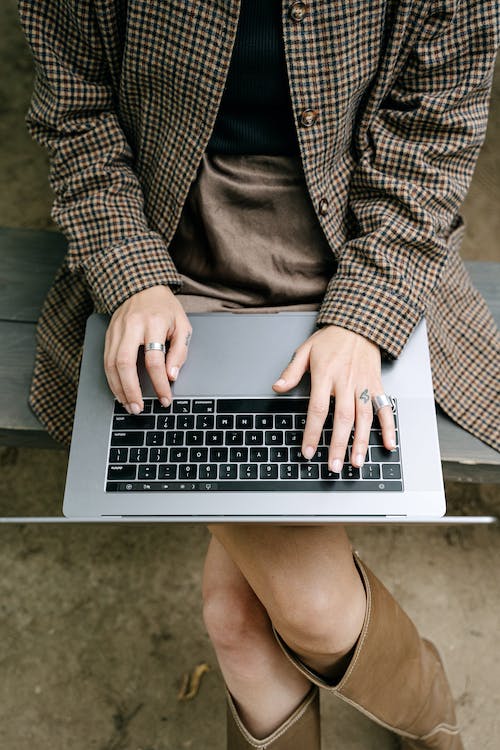 Free Woman in Brown Checkered Coat Using a Laptop Stock Photo