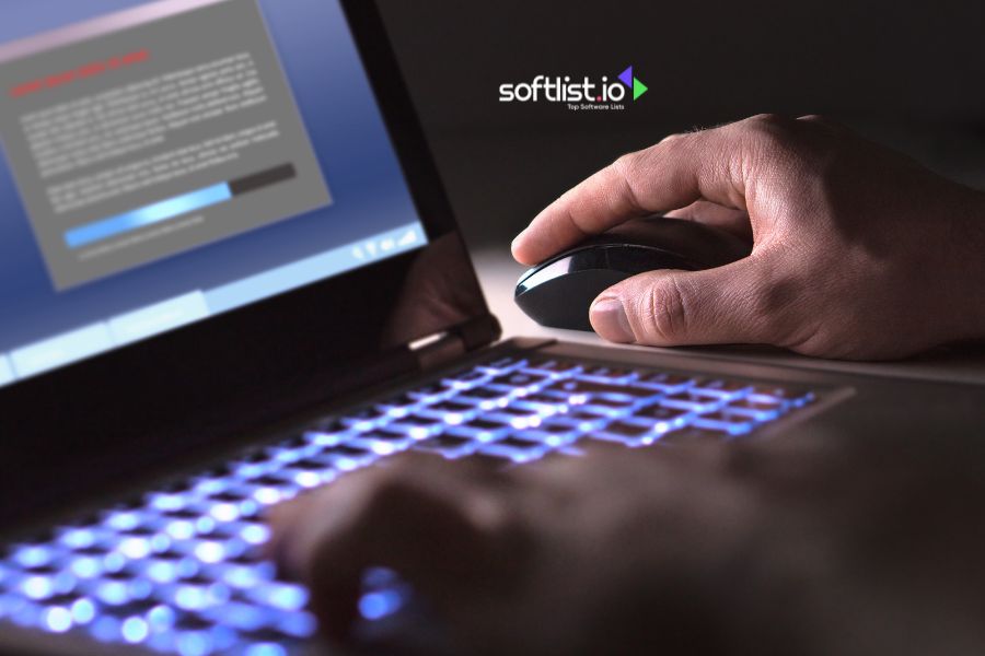 Hand using a mouse beside a laptop with a glowing keyboard.