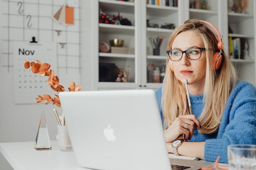 Free Woman Using Laptop and Wearing Headphones Stock Photo