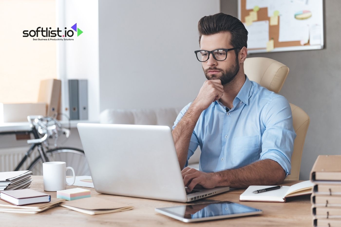 Focused man working on a laptop with softlist.io logo in a modern office setup