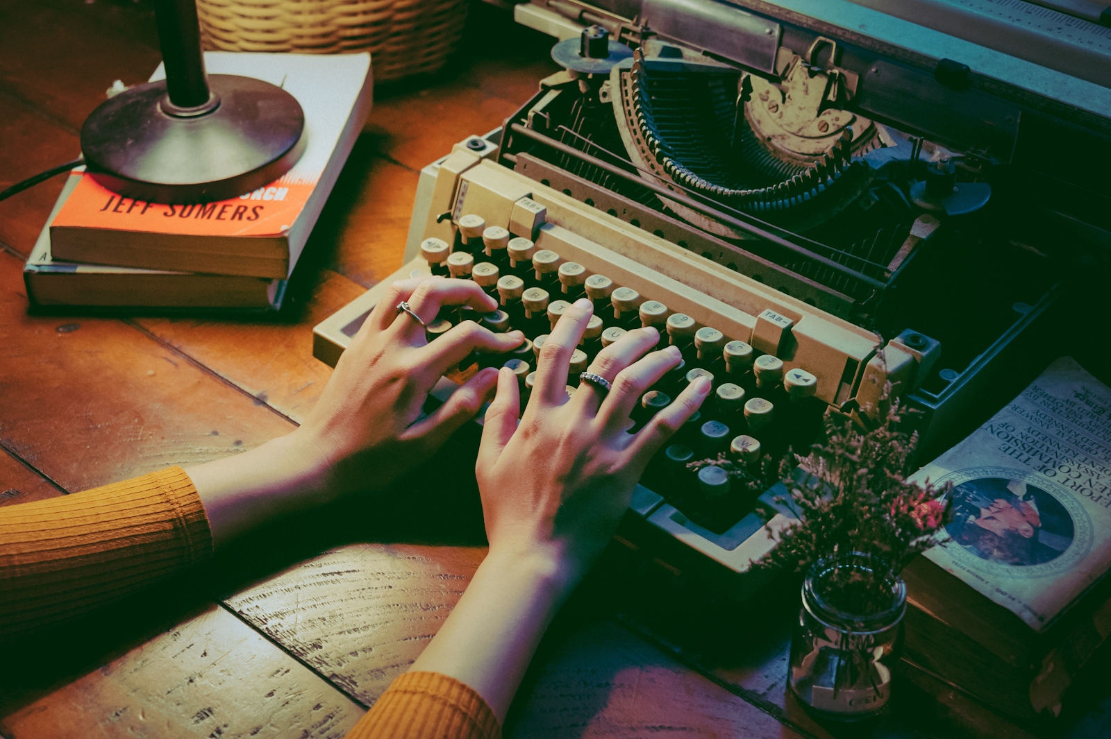 A photo of a woman's hands typing on an old typewriter.