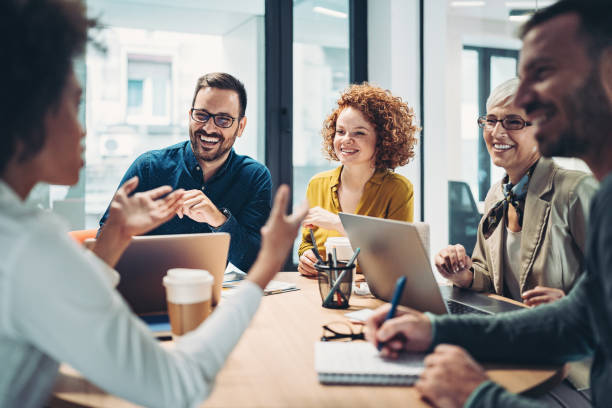 Business people sitting around the table and talking Multi-ethnic group of business persons having a meeting in the office workspace stock pictures, royalty-free photos & images