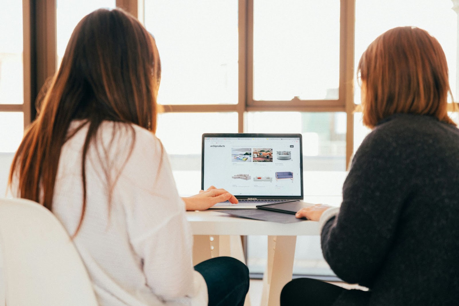 Two people are looking at a laptop on a table.