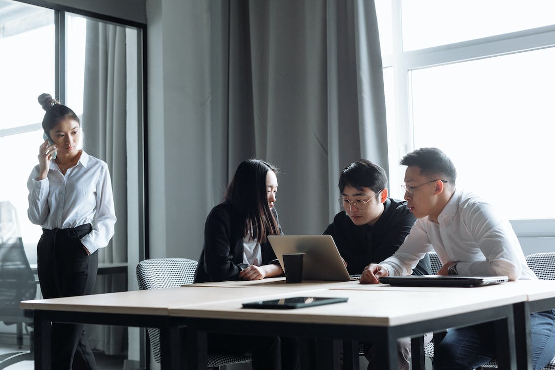 Free Young Business People Working and Discussing In Front of a Laptop Inside an Office Stock Photo