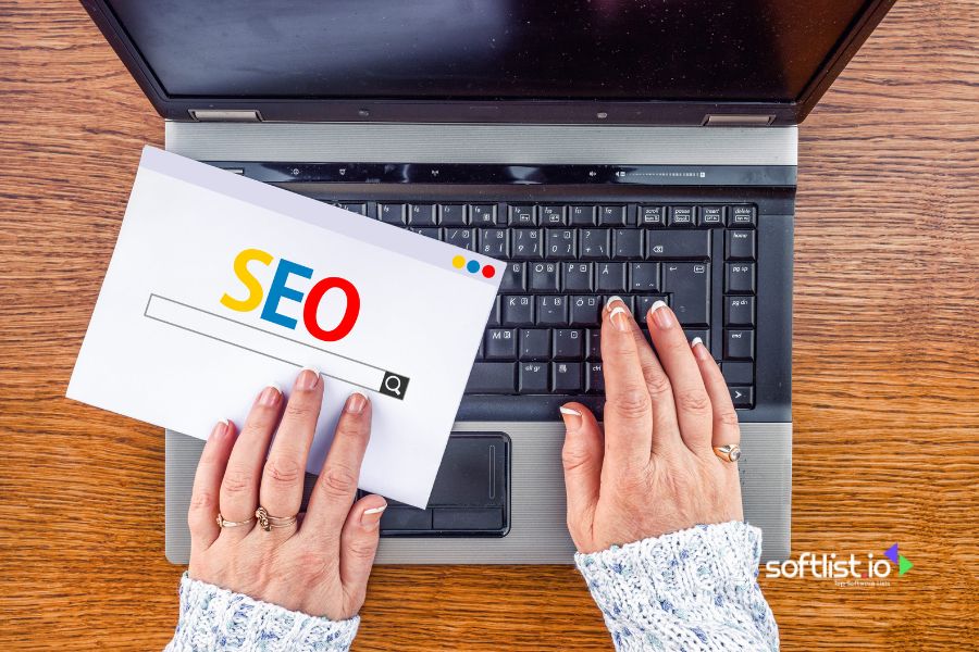 Hands holding SEO paper above a laptop keyboard.