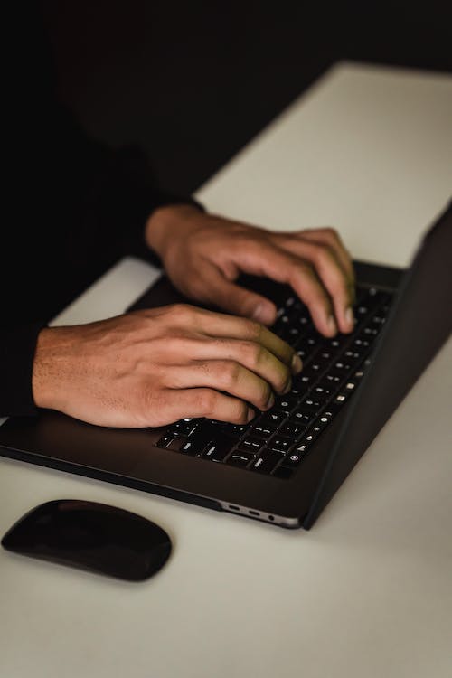 Free Crop unrecognizable man typing on laptop keyboard Stock Photo