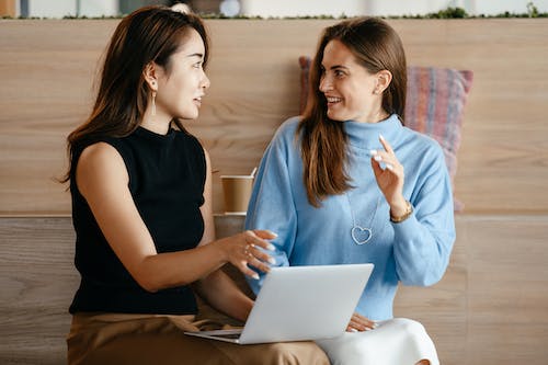 Free Young multiethnic business partners speaking about strategy of job while browsing netbook in contemporary workplace Stock Photo