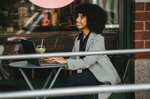 Free Smiling black freelancer typing on laptop on cafe terrace Stock Photo